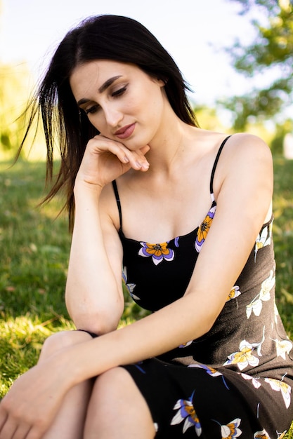 Cheerful young beautiful woman lying outdoors on green grass in city park.