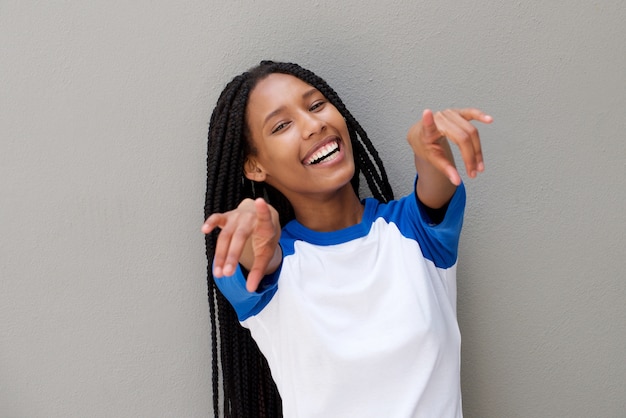 Cheerful young black woman pointing fingers against gray background