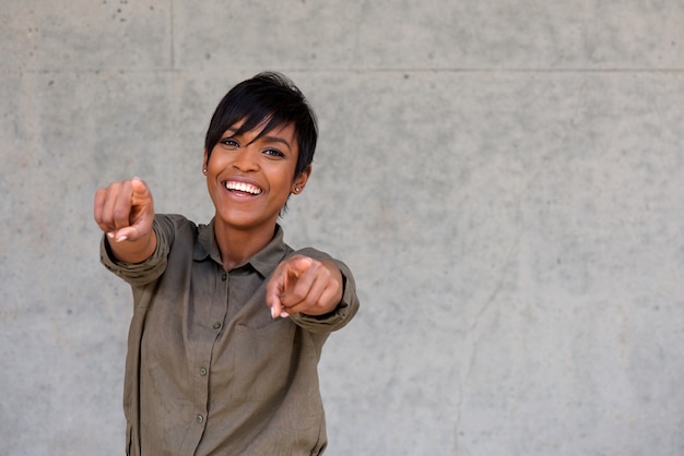 Cheerful young black woman pointing fingers with copy space