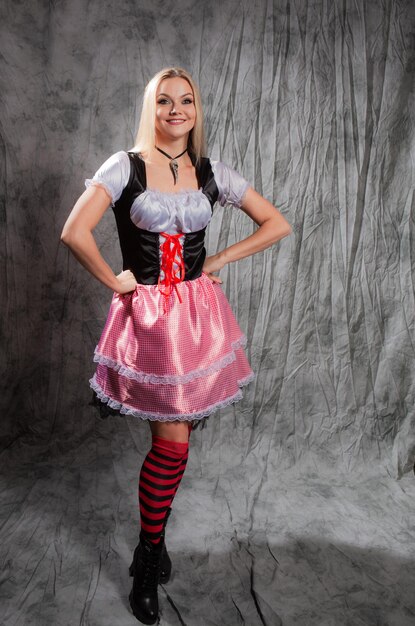 Cheerful young blonde in a bavarian suit portrait in the studio on gray