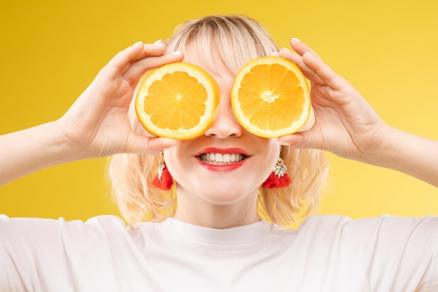 Cheerful young blonde posing with fresh oranges