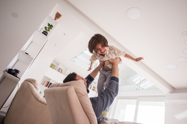 Cheerful young boy having fun with father on sofa