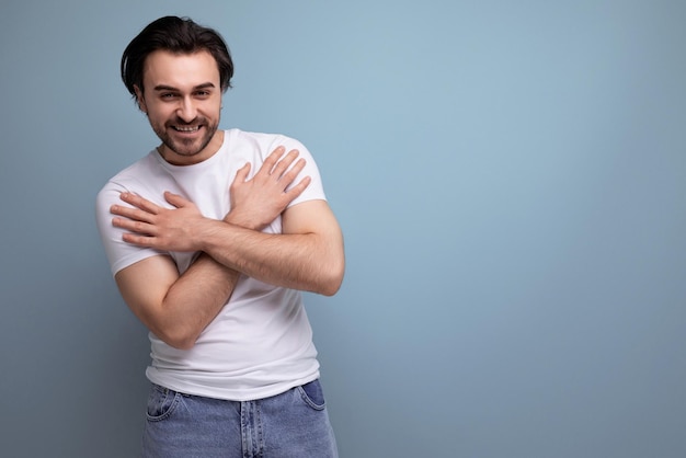 Cheerful young brunette guy in a white tshirt and jeans