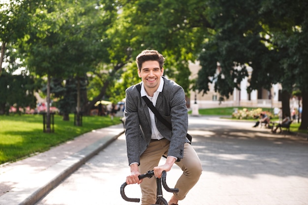 Cheerful young businessman riding on a bicycle