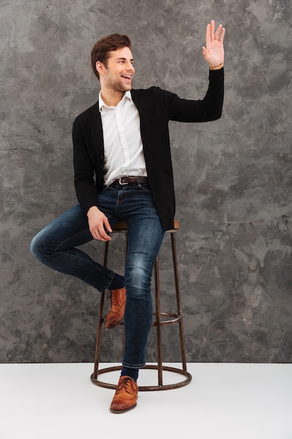 Cheerful young businessman waving to friends.