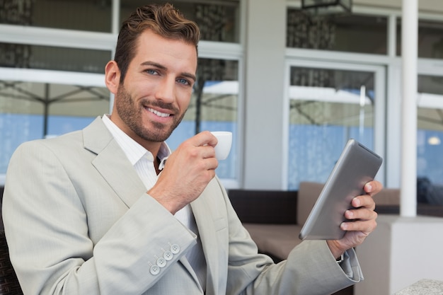 エスプレッソを飲むタブレットで働く明るい若い実業家