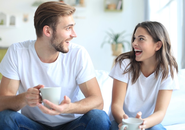 Cheerful young couple in the morning at home in the living room and laughing.