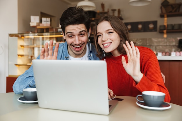 Cheerful young couple sitting at a cafe table together