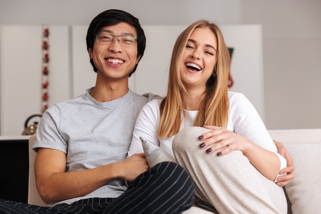 Cheerful young couple, sitting together on a couch at home