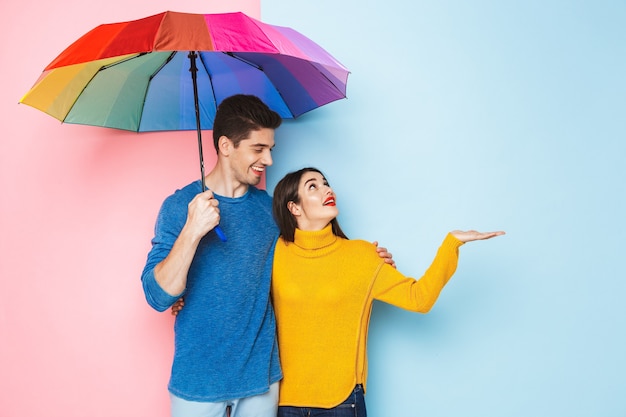 Cheerful young couple standing with an umbrella