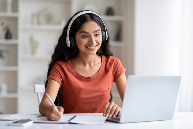 Cheerful young eastern woman student have online lesson home interior