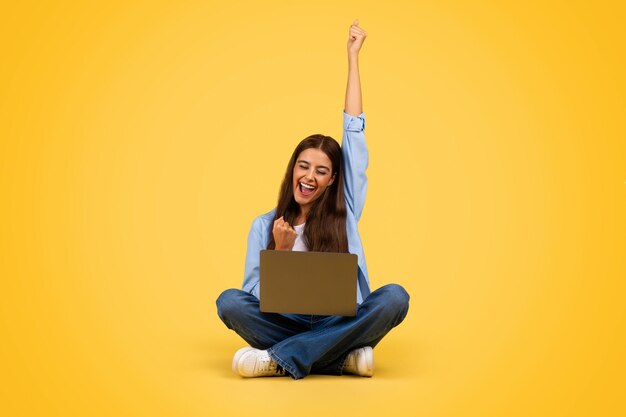 Cheerful young european student woman with laptop rise hand up