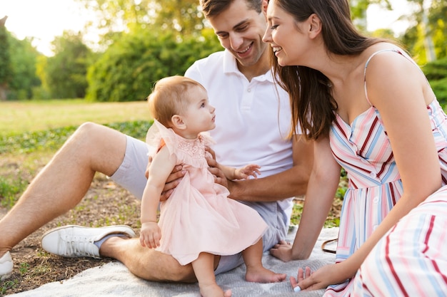 Cheerful young family with little baby girl spending time together