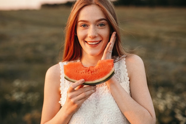 Cheerful young female eating sweet watermelon