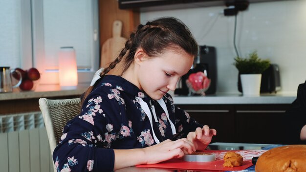 Piatto di cottura di riempimento della ragazza allegra con la pasta di pasticceria.