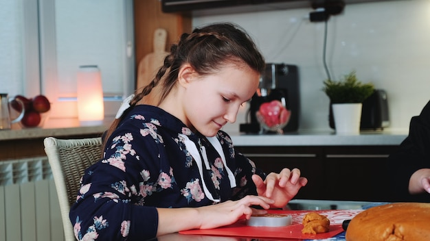 Cheerful young girl filling baking dish with pastry dough.