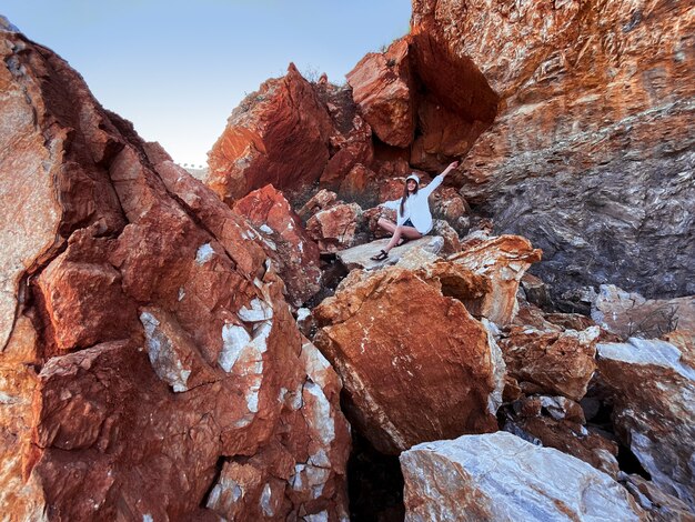 Cheerful young girl sits in the rocks in stone canyon