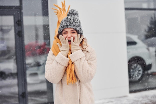 立って笑顔と屋外で笑顔の陽気な若い女の子。雪が降っています。