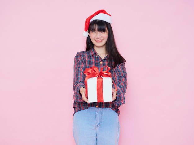 Cheerful young girl wearing santa hat giving gift box isolated