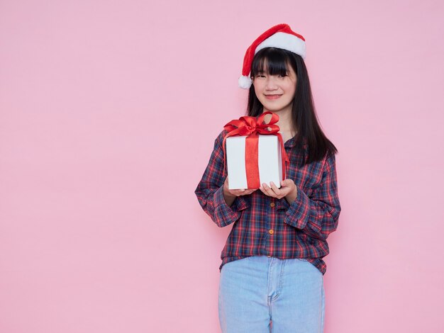 Cheerful young girl wearing santa hat with holding gift box