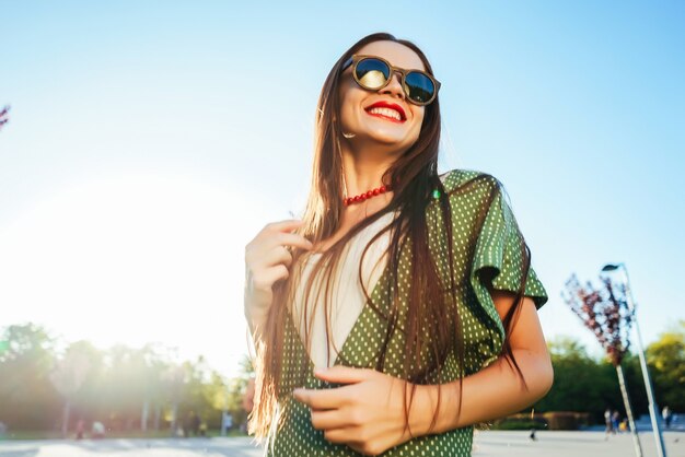 Cheerful young girl with long hair walking in the park, laughing. sunny day