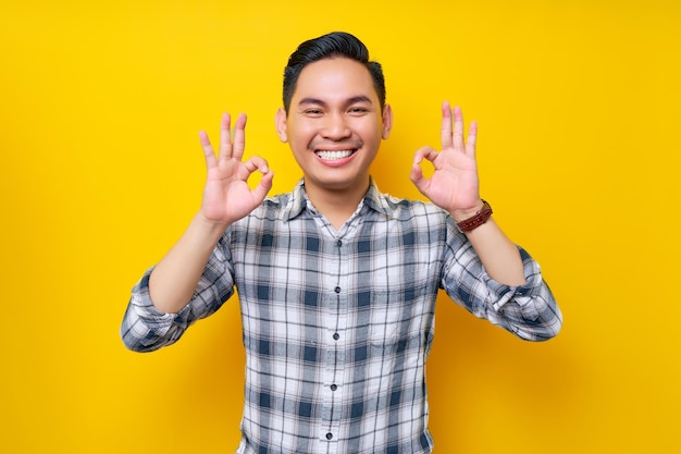 Cheerful young handsome Asian man wearing casual clothes showing okay sign isolated on yellow background People lifestyle concept