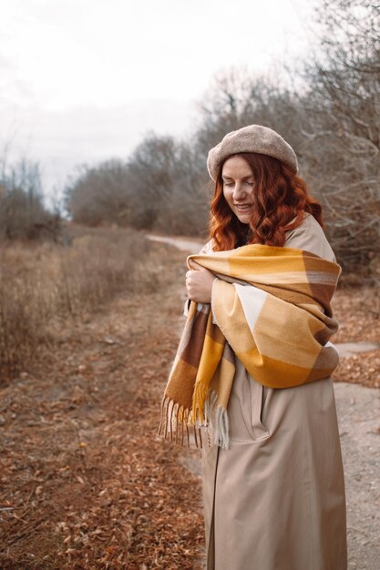 Foto giovane ragazza felice allegra che posa con la sciarpa lavorata a maglia. donna sorridente che guarda l'obbiettivo durante la stagione autunnale. vestiti alla moda autunnali
