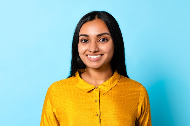 Cheerful young hindu lady posing for headshot against blue background