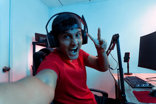 Cheerful young Hispanic man taking a selfie inside a video game room