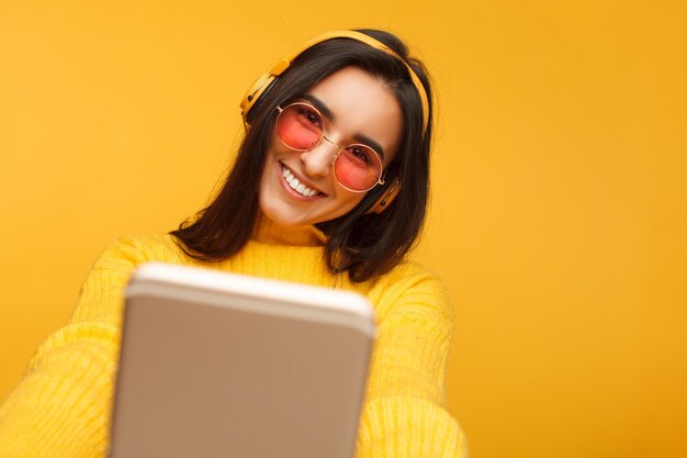 Cheerful young hispanic woman taking a selfie on yellow