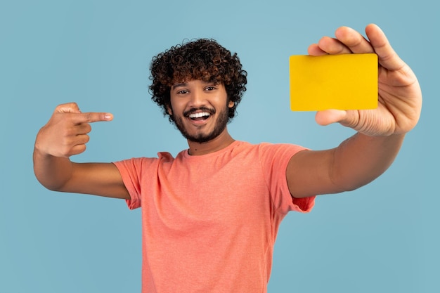 写真 クレジットカードを指している陽気な若いインド人