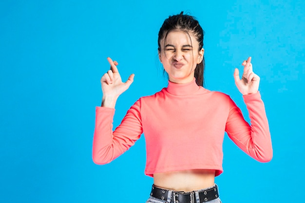 Photo cheerful young lady raised her fingers and standing on blue background high quality photo