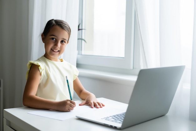 온라인 전자 학습 시스템을 통해 공부하는 노트북 컴퓨터를 사용하는 쾌활한 어린 소녀