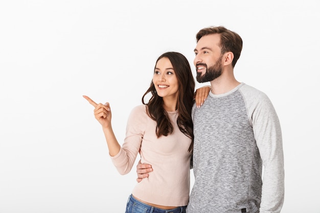 Cheerful young loving couple pointing.