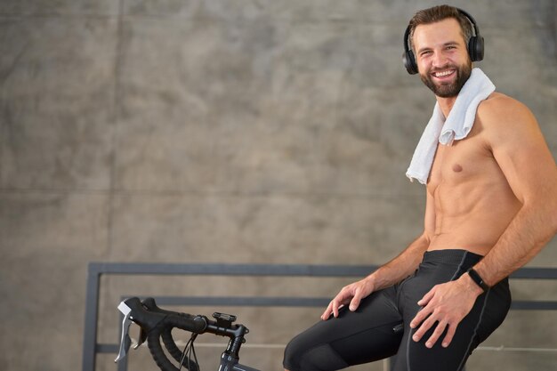 Cheerful young man having stationary bike workout at home