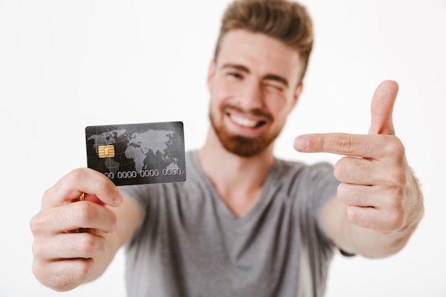 Cheerful young man holding credit card pointing.