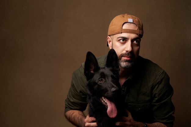 Cheerful young man hugging his dog, indoors portrait