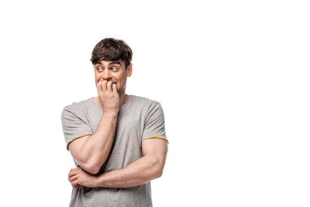 Cheerful young man looking away while holding hand near face isolated on white