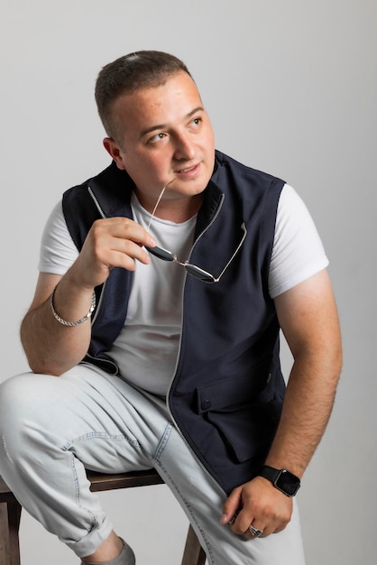 A cheerful young man model in a sleeveless regular solid jacket and a black sunglass posing in multi