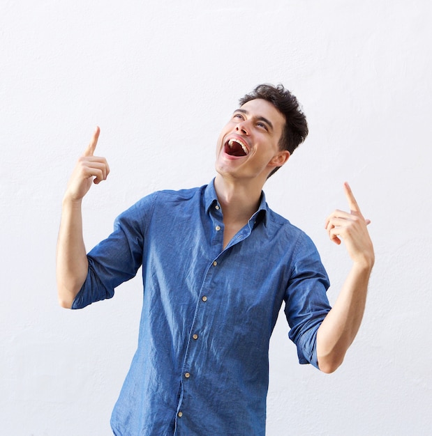 Cheerful young man pointing fingers to copy space