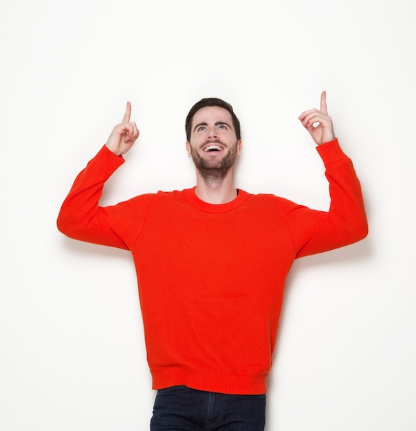 Cheerful young man pointing fingers up