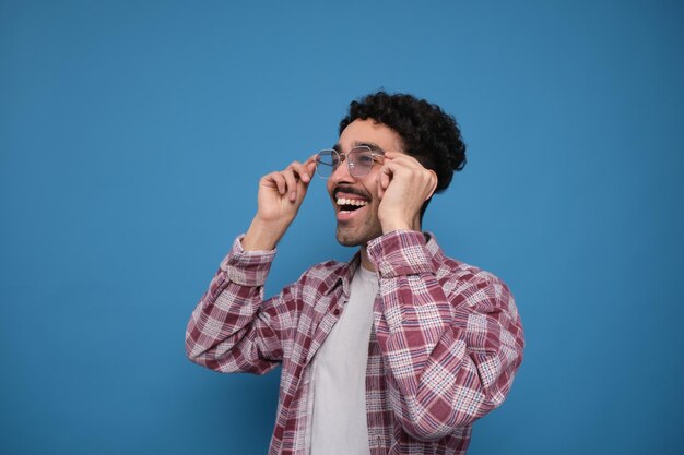 Cheerful young man putting on eyeglasses