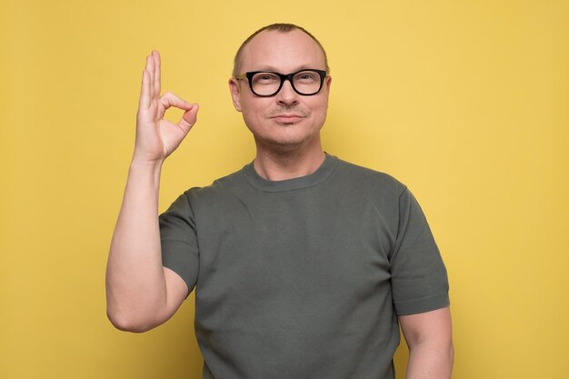 Cheerful young man showing okay gesture approving his choice