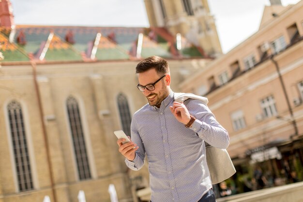 Cheerful young man uses mobile phone on street