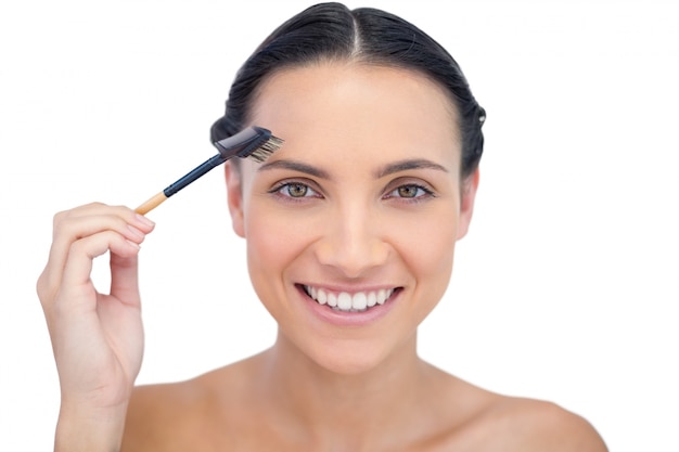 Cheerful young model using eyebrow brush