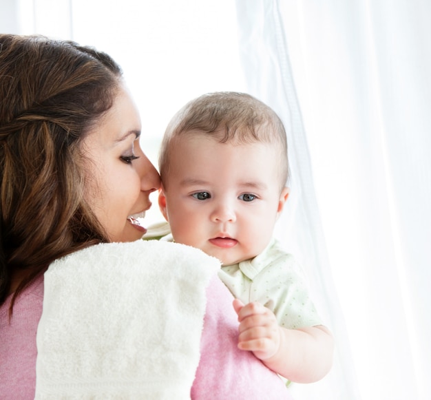 Cheerful young mother taking care of her adorable baby