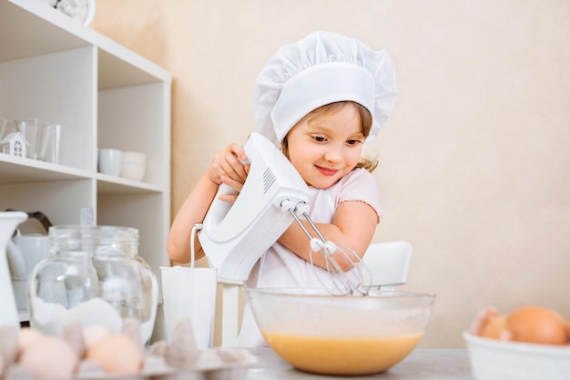 Foto un'allegra giovane assistente di madri impasta l'impasto per una ricetta passo passo di una torta su una tavoletta