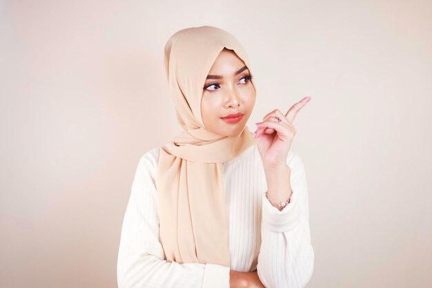 Cheerful young Muslim Asian woman pointing side to copy space with smile