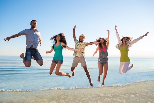 Cheerful young people jumping on the beach.