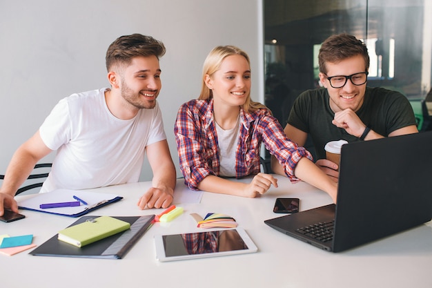 Cheerful young people sit at table in room